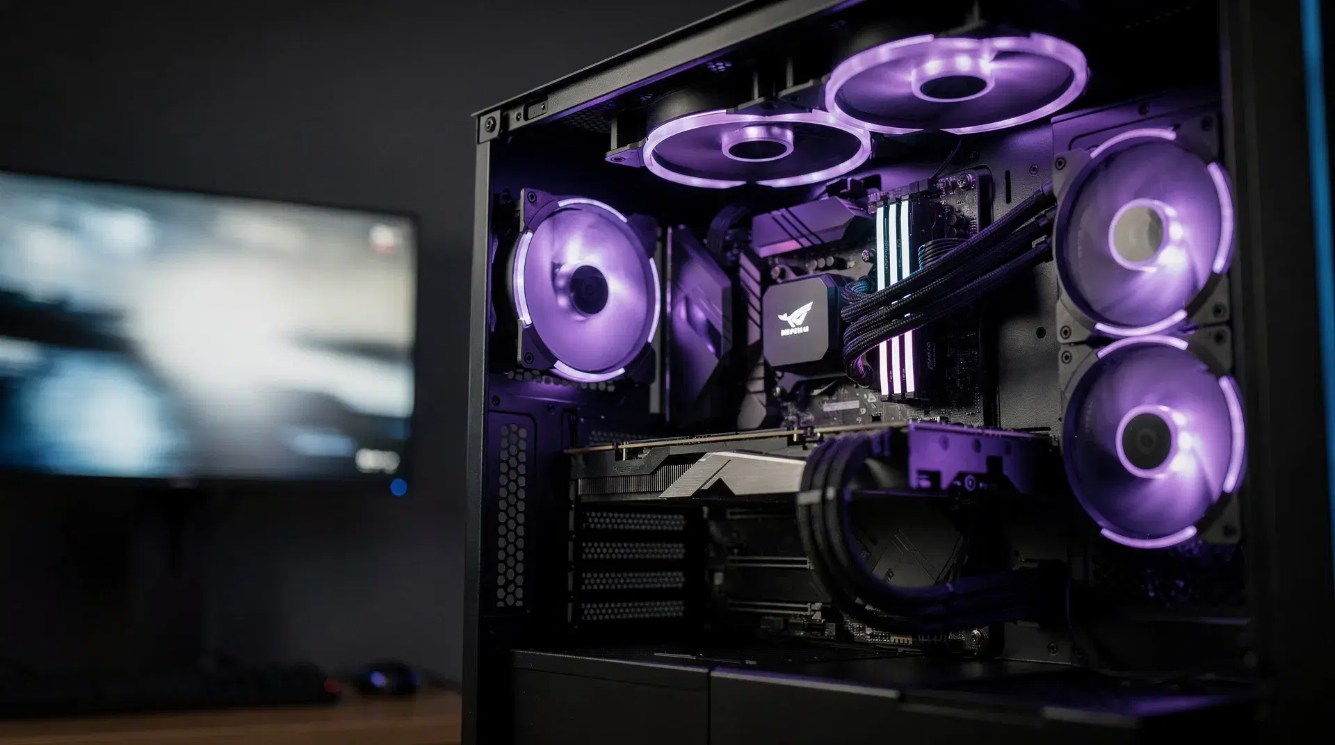 A high-performance gaming PC with glowing fans and motion-blurred high-refresh display